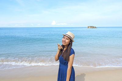 Young woman standing on beach against sky