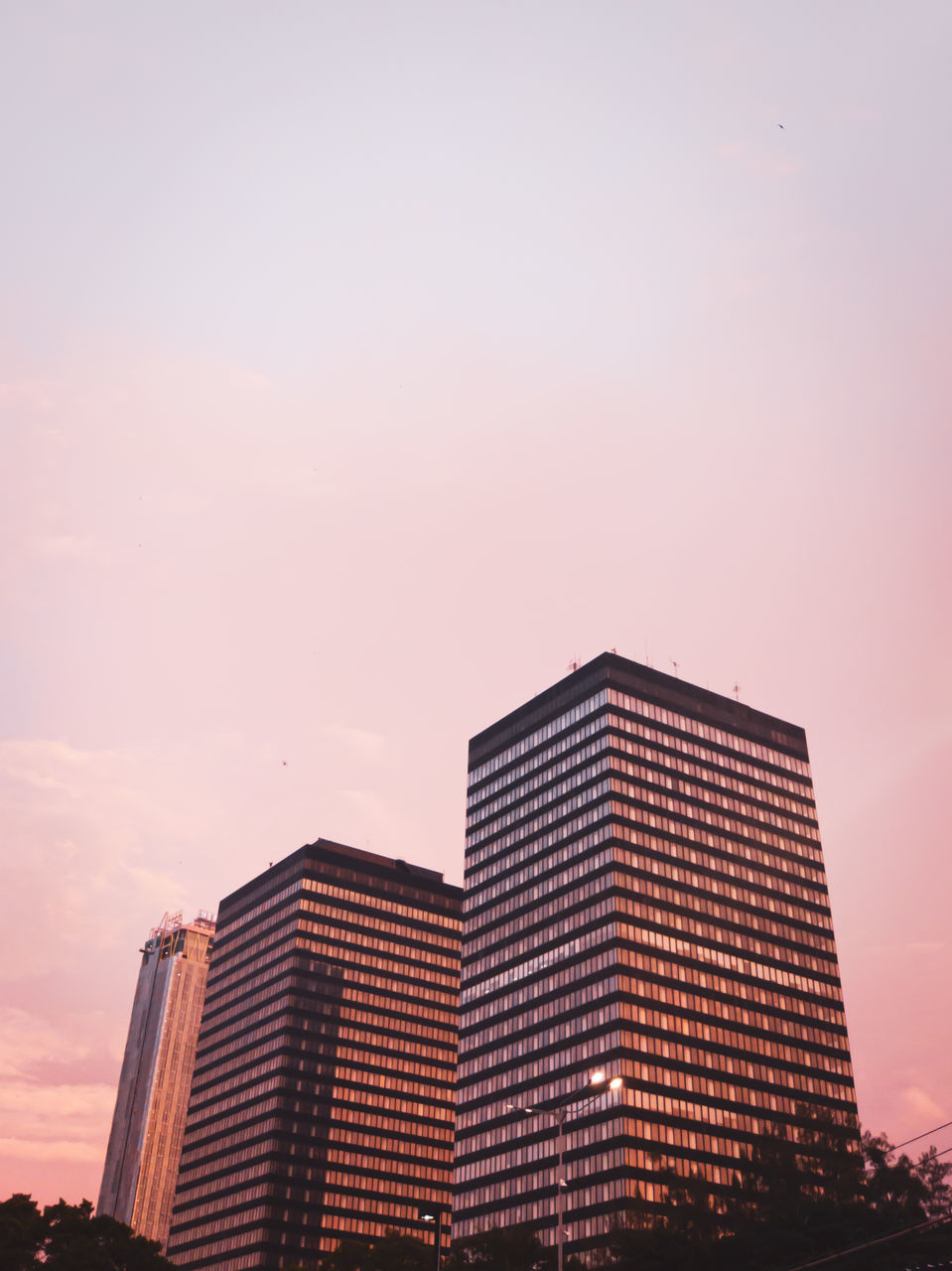 LOW ANGLE VIEW OF MODERN BUILDING AGAINST SKY AT SUNSET