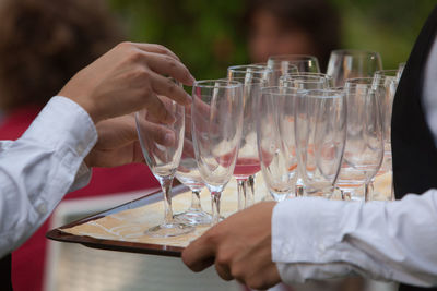 Cropped hands of waiters with glasses