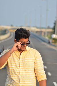 Young man using mobile phone while standing on road