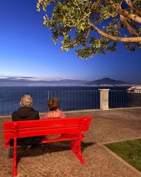 Empty bench by sea against sky