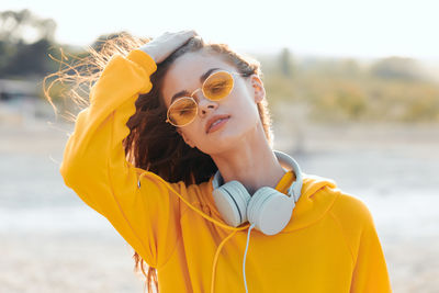 Young woman wearing sunglasses while standing at beach