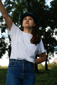 Portrait of a sad young woman with brown hair wearing a hat outdoors. green nature background. 