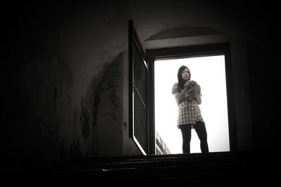 Portrait of woman standing against window