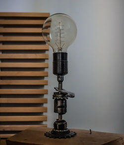 Close-up of light bulb on table against wall