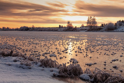 The sun rises over the frozen river at the rural finland. 