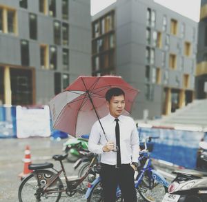 Man with umbrella standing in city