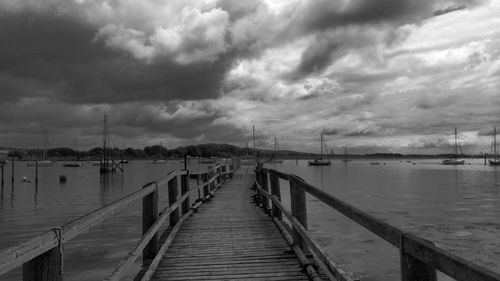 Pier on sea against cloudy sky