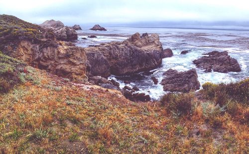 Rocks on sea shore against sky