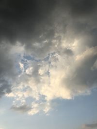 Low angle view of sunlight streaming through clouds