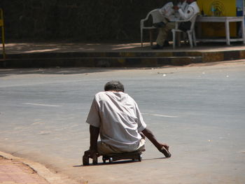 Disabled beggar on cart over road in city
