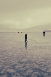 Rear view of kid ice skating on a frozen lake against sky