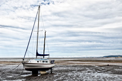 Sailboat moored on beach against sky