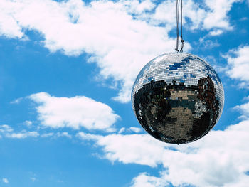 Low angle view of disco ball hanging against sky