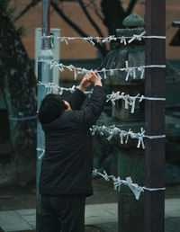 Rear view of woman hanging wishes in temple