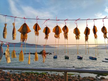 Clothes drying on rope at beach against sky