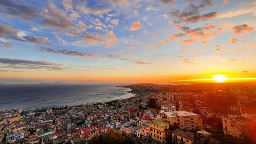 High angle view of townscape by sea against sky during sunset