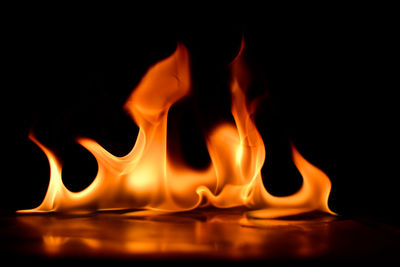 Close-up of burning candle in black background