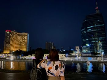 Back portrait of two women looking at night city lights