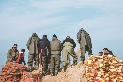 Rear view of people at market stall against sky