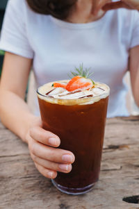 Midsection of woman with drink on table