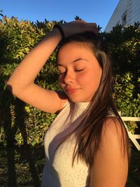 Portrait of beautiful young woman standing against plants