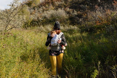 Woman carrying baby in a carrier walking in nature