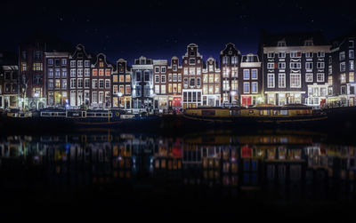 River by illuminated buildings in city at night