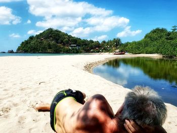 People relaxing on beach against sky