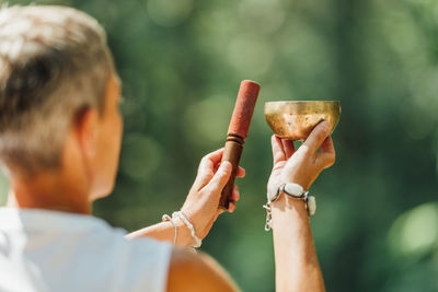 Woman performing sound healing therapy in nature with tibetan singing bowl