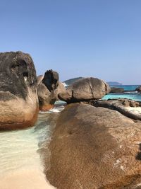 Rocks on beach against clear sky