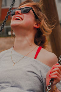 Close-up of cheerful woman enjoying swing at playground