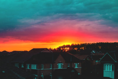 Houses against dramatic sky during sunset