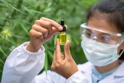 Woman holding essential oil bottle at green house