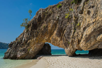 Rock formation on beach against clear sky