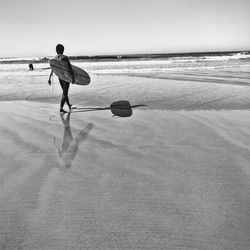 Man playing on beach against clear sky