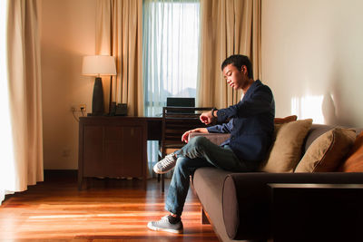 Side view of woman using mobile phone while sitting at home