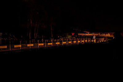 Illuminated railroad tracks against sky at night