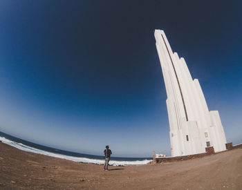 Woman on sand against clear blue sky