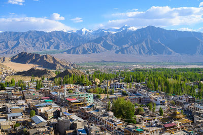 Aerial view of townscape and mountains against sky