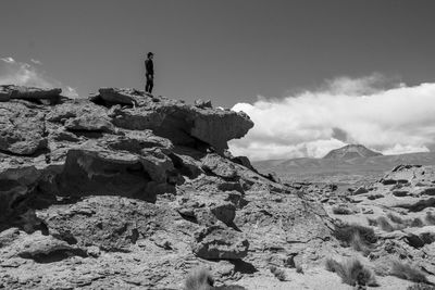 Man standing on rock against sky