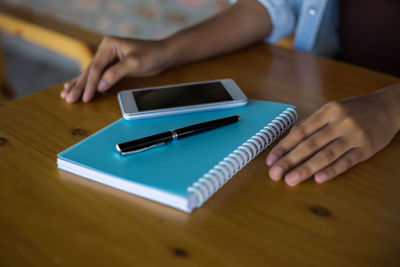 Midsection of man using smart phone on table