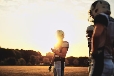 Side view of couple standing against sky during sunset