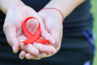 Midsection of woman with aids awareness ribbon on hand