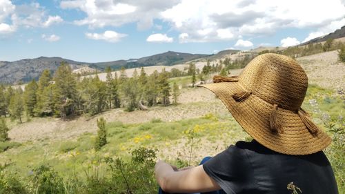 Woman wearing sun hat gazing out at mountains and nature