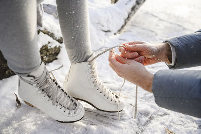 Father tying lace on daughter's ice skates