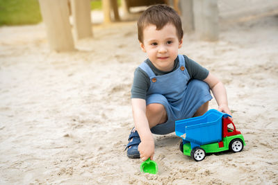 Boy playing with toy on sand at beach