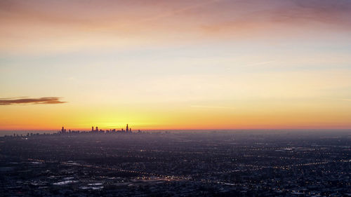 High angle view of buildings and sea against sky during sunset