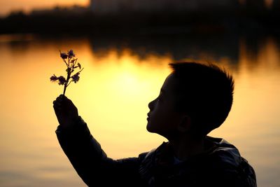 Close-up of silhouette boy against sky during sunset