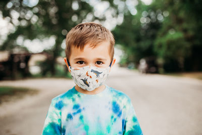Preschool age boy standing outside wearing homemade fabric mask